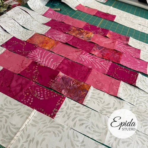 Quilted fabric strips arranged on a cutting mat with 'Epida Studio' branding.
