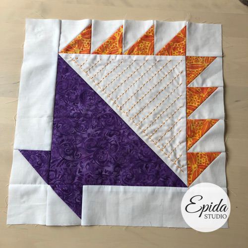 white, purple and orange quilt block with hand embroidery.