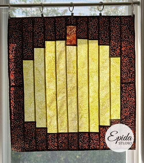 Window hanging featuring a yellow pumpkin on dark background.