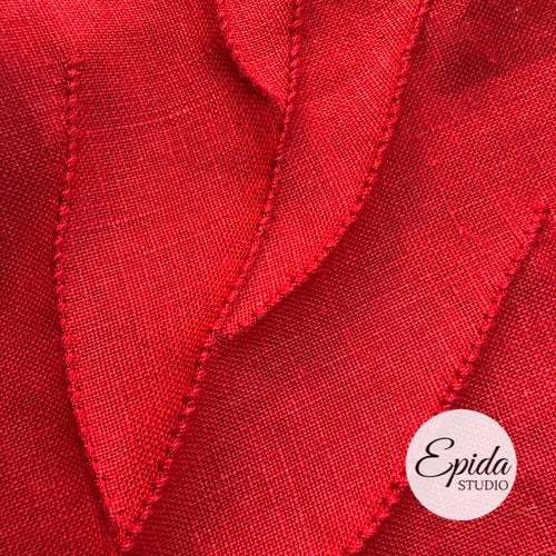 close up of hand stitching on red leaf.