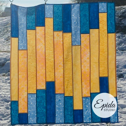 Blue and yellow pojagi window hanging outside in the snow.