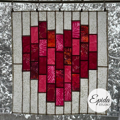 Quilt with red and pink pattern hanging outdoors