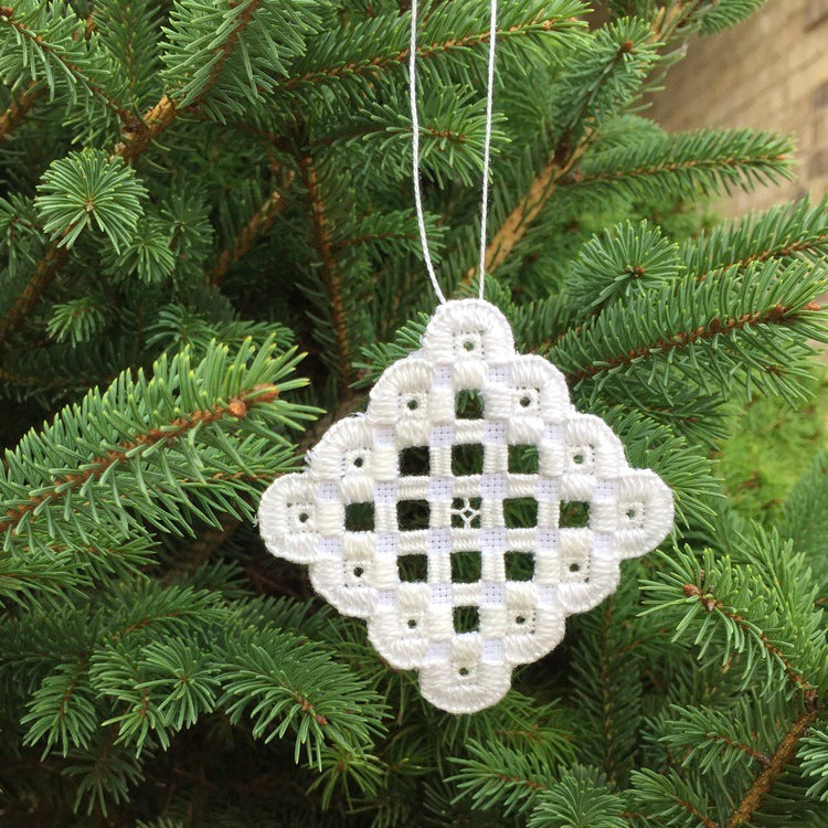 white hardanger ornament hanging on tree.