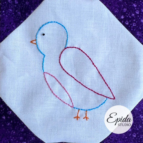 Embroidered bird design on white fabric with a purple background, featuring the Epida Studio logo.