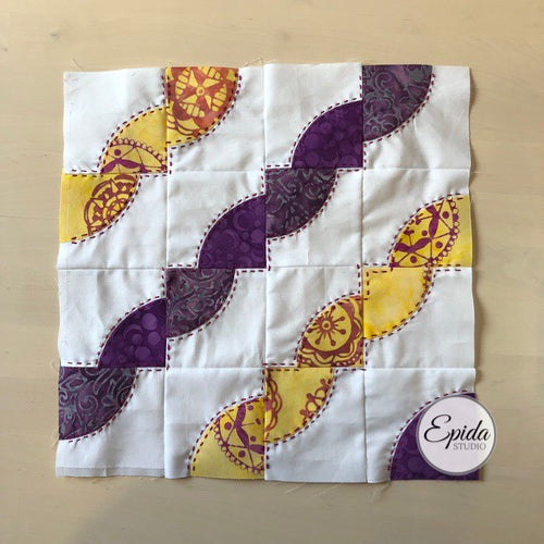 purple and yellow drunkards path quilt block.