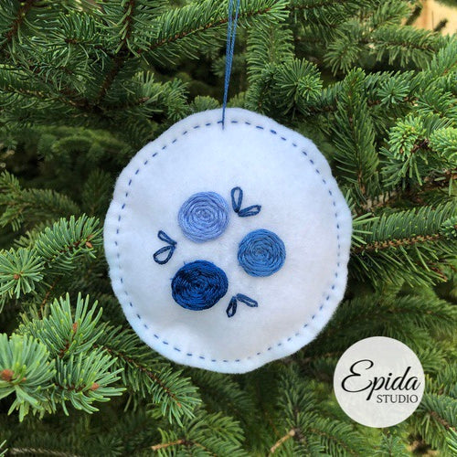 white felt ornament with blue embroidery.