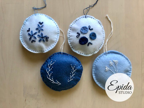 four felt Christmas ornaments with hand embroidery.