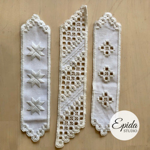 three hand embroidered bookmarks, white thread on white fabric.