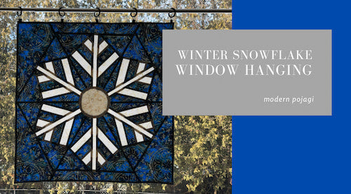 Winter snowflake window hanging with blue and black design on a gray background