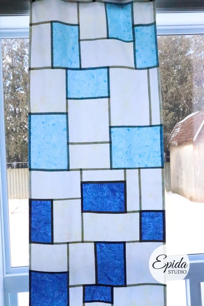 close up of blue patchwork window hanging.