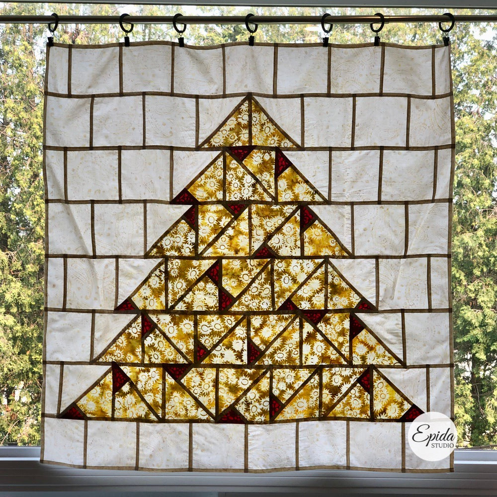 Batik window hanging of gold Christmas tree on white background.