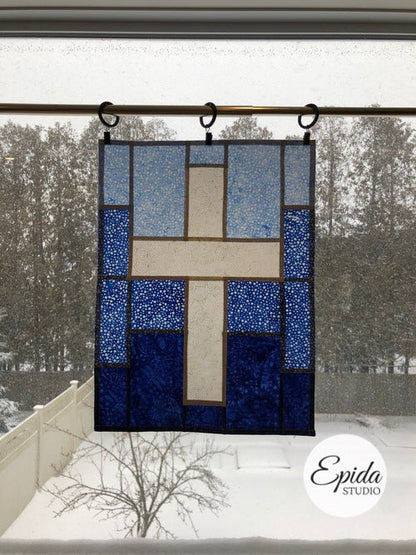 small cross window hanging in blue and white.