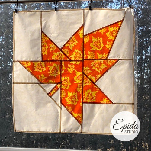 Orange maple leaf stained glass patchwork window hanging.