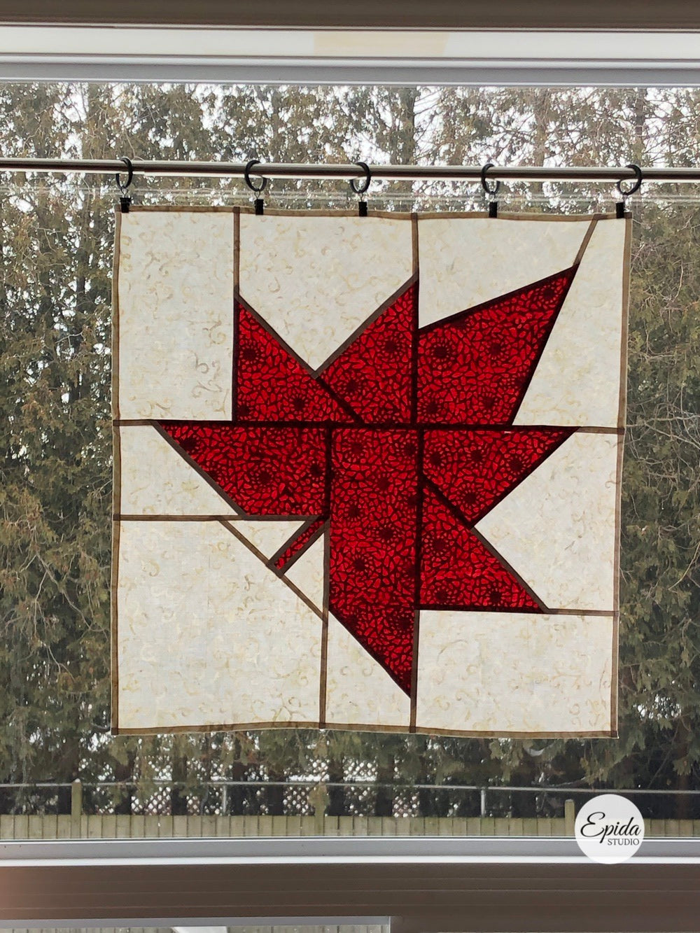 reversible pojagi maple leaf hanging in a window.