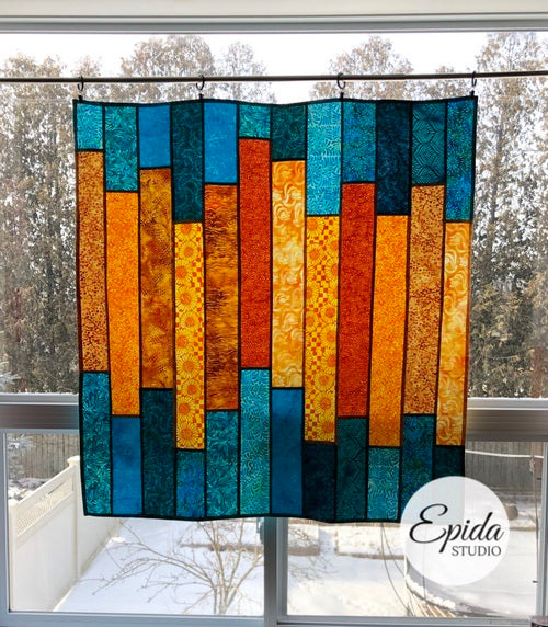 Glimmer stained glass window hanging in gold and teal batik fabric.