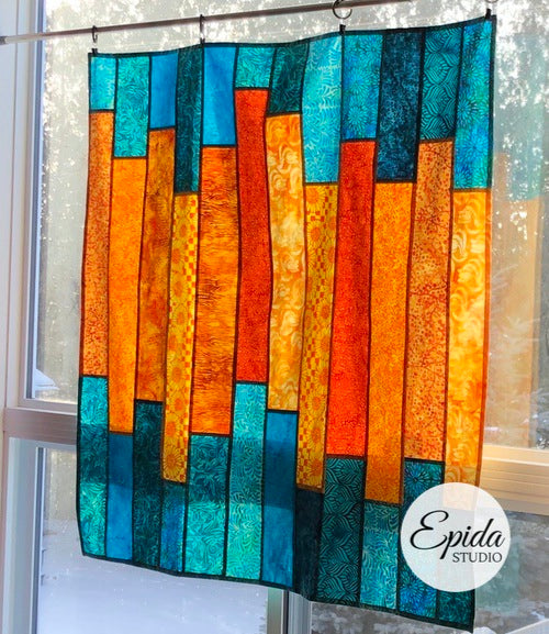 Pojagi window hanging in orange and blue fabric.
