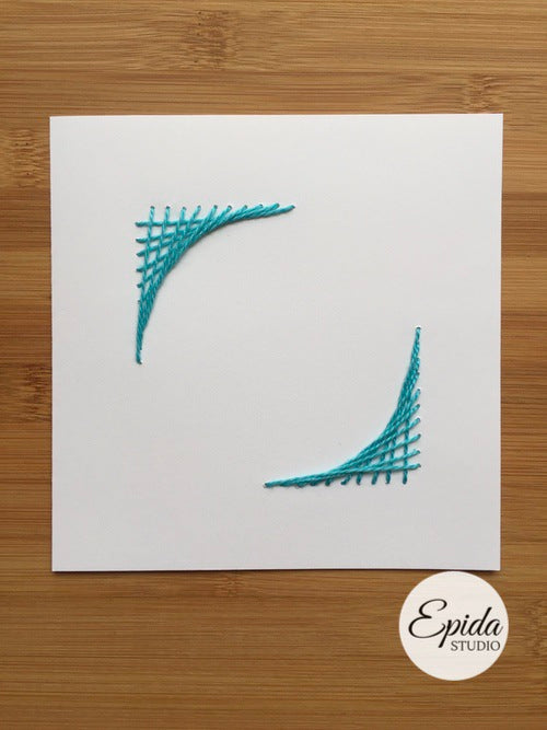 Greeting card with hand-stitched corner design in blue thread.