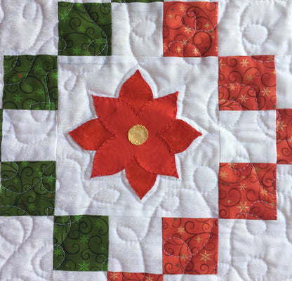 close up of poinsettia applique on quilted table runner.