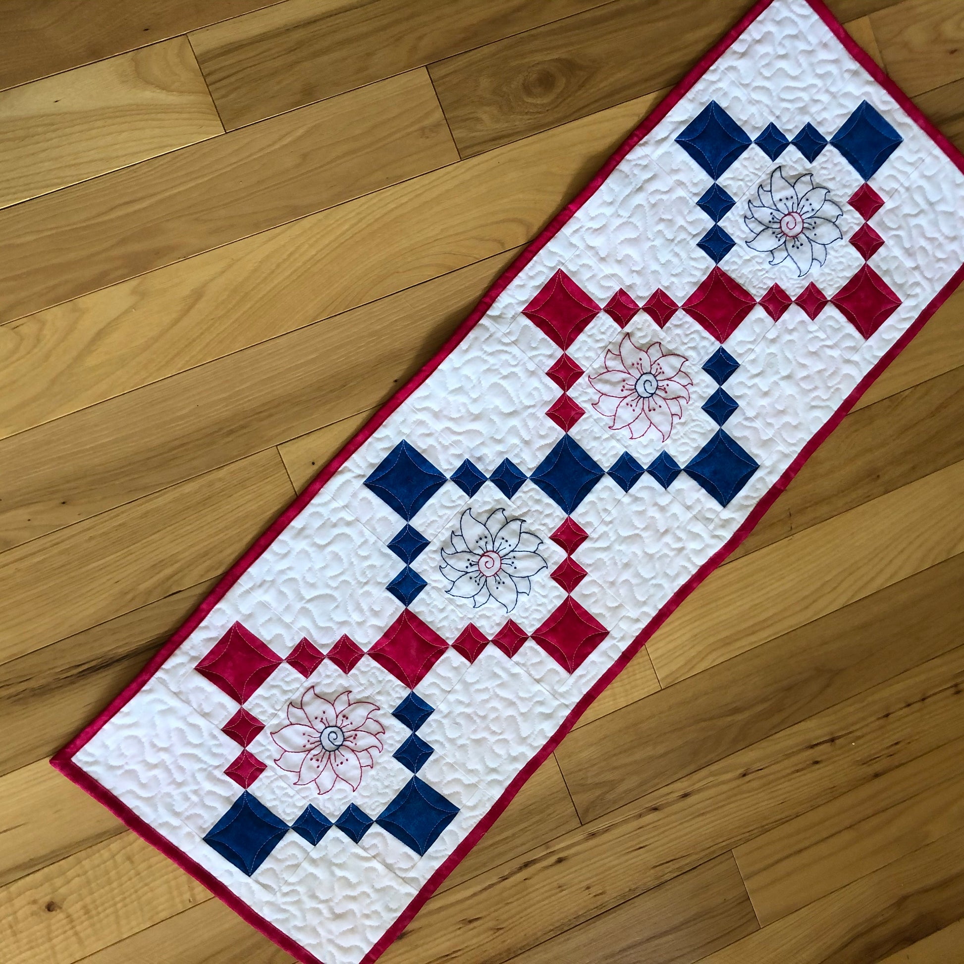 pink and blue table runner with embroidered flowers.