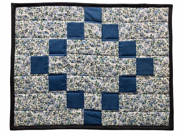 quilted floral placemat with blue chain.